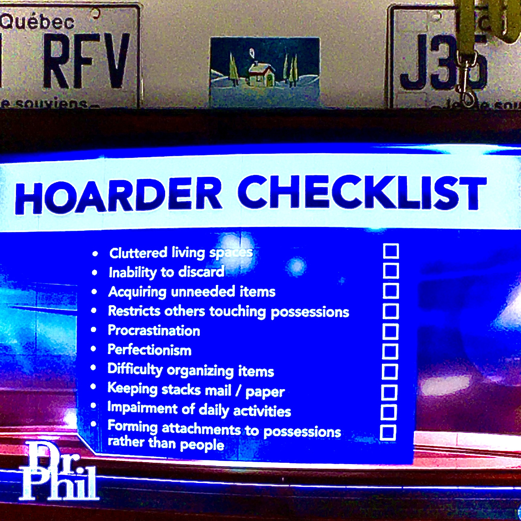 Image of a TV screen displaying a graphic of a hoarding checklist being shown on the Dr. Phil show with the Dr. Phil logo at the bottom of the screen. Two Québec licence plates in the background as well as a greeting card showing an illustration of a home in a winter setting with smoke rising from the chimney.